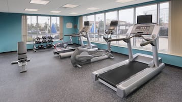 Academia com esteiras, halteres e equipamentos de ginástica.