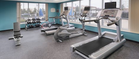 Un gimnasio con cintas de correr, mancuernas y equipamiento de ejercicio.