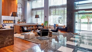 A spacious lobby with a marble floor, a reception desk, seating area with sofas and armchairs, a fireplace, and large windows offering views of the outdoors. - Renaissance Atlanta Midtown Hotel (Atlanta)