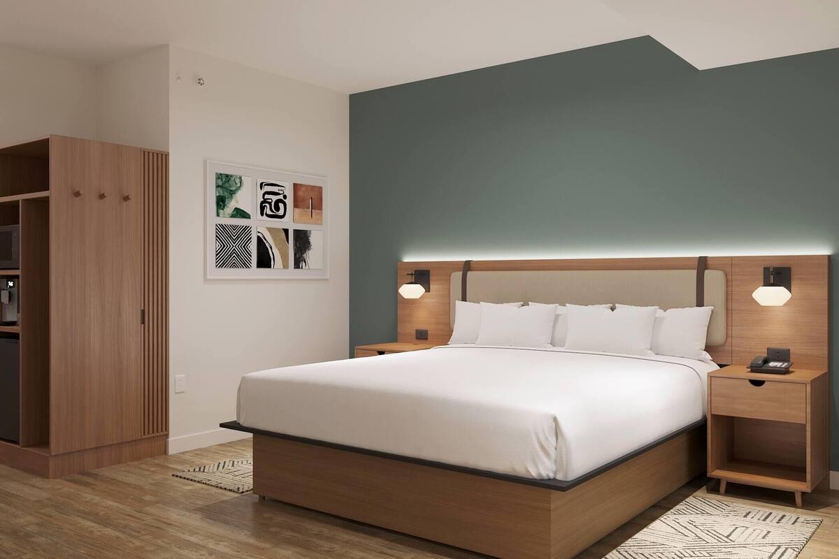 Ein modernes Schlafzimmer mit einem großen Bett, einem Holzschrank und einer Wandleuchte.