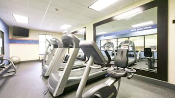 A gym with treadmills, exercise balls, and a mirrored wall.