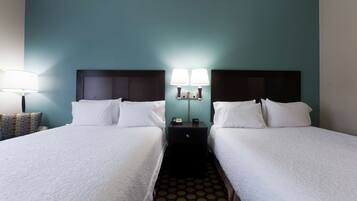 A hotel room with two beds, a nightstand with a lamp, and a patterned floor.