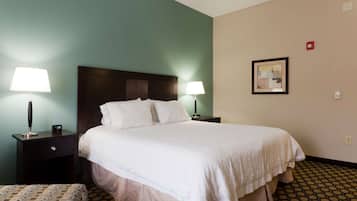 A hotel room with a large bed, two bedside tables with lamps, a headboard, a framed picture on the wall, and a patterned floor.