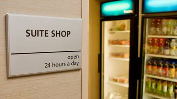 A sign for the Suite Shop, open 24 hours a day, next to a refrigerator stocked with beverages.