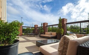 An outdoor patio with seating, potted plants, and a brick fireplace. - Hampton Inn Greenville (Greenville)