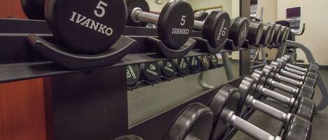 Eine Reihe von 5-Kilogramm-Hanteln mit der Aufschrift 'Ivanko' an einem Stativ im Fitnessstudio.
