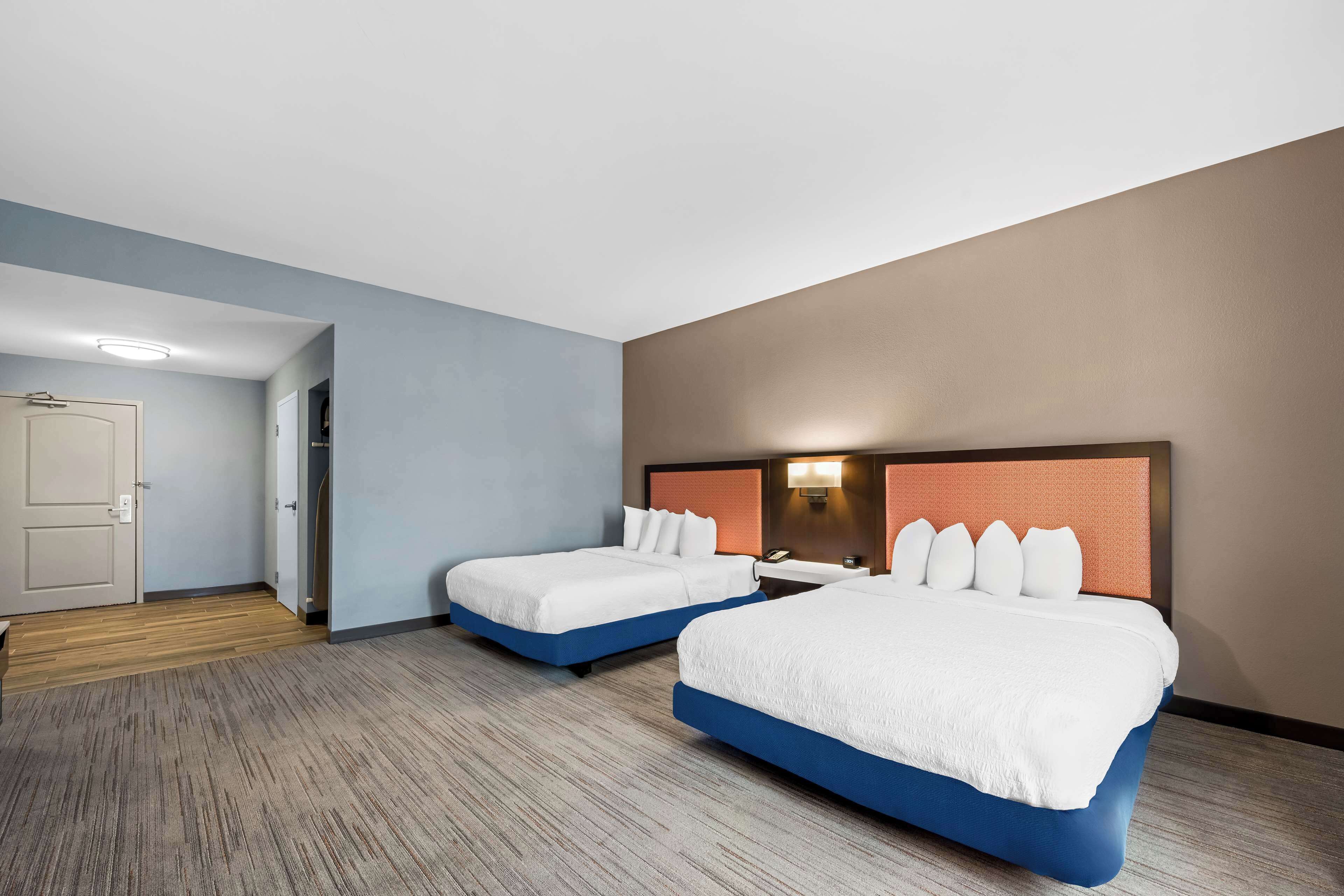 Une chambre d’hôtel avec deux lits, un plancher en bois et une porte donnant sur une autre pièce.