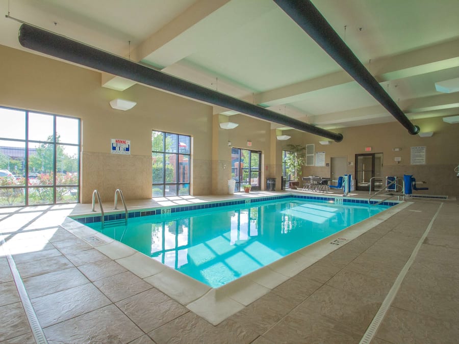 Una piscina interior con ventanas transparentes, un letrero de salvavidas y un indicador de profundidad.