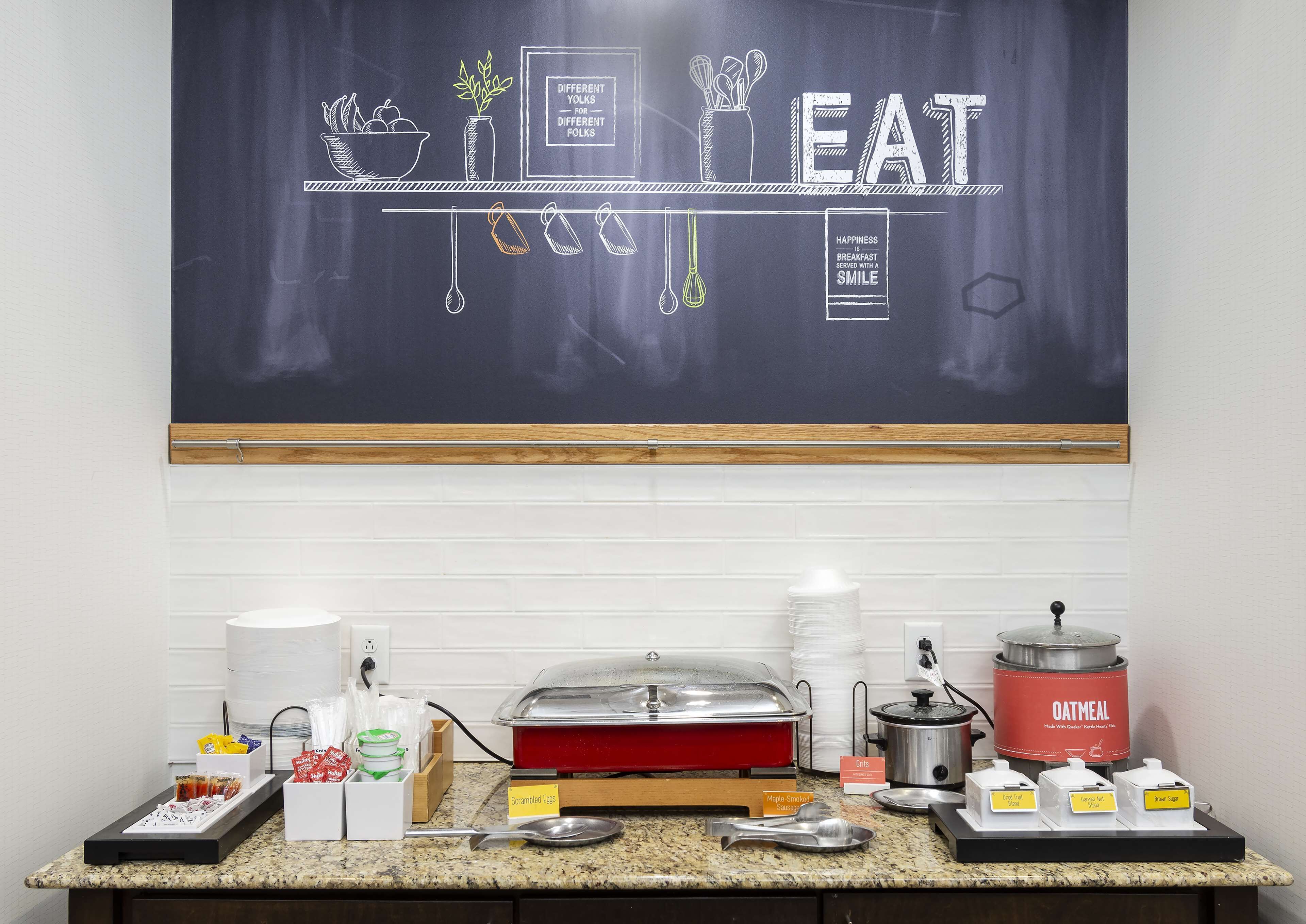 A breakfast buffet setup with various food items and a chalkboard displaying 'DIFFERENT YOLKS FOR DIFFERENT FOLKS'.