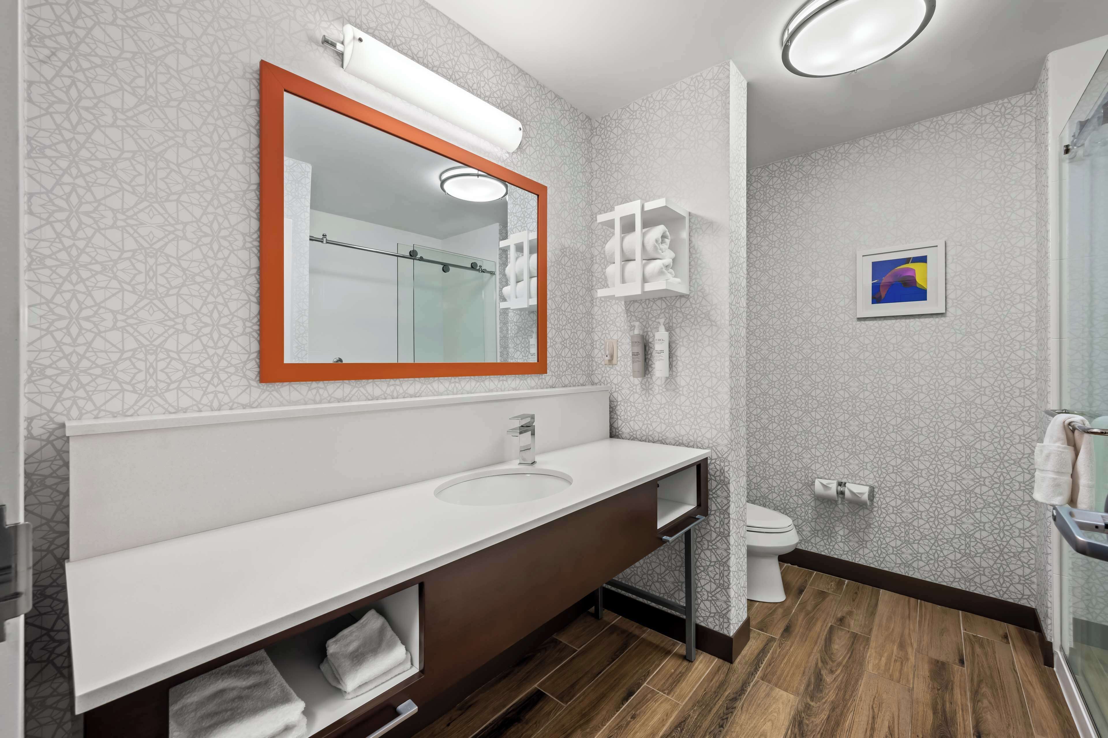 Ein modernes Badezimmer mit einem großen Spiegel, zwei Waschbecken, einer Toilette und einer Duschkabine.