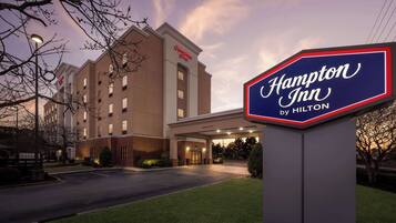 Ett Hampton Inn-hotell som tillhör Hilton-kedjan, med en väl upplyst entré och fri sikt över byggnadens fasad.
