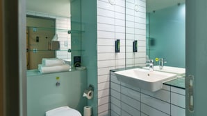 Une salle de bain moderne avec une douche à parois de verre, des toilettes blanches et un lavabo surmonté d’un miroir.