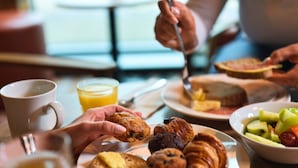 Une table dressée pour le petit-déjeuner, avec des viennoiseries, un muffin et un bol de fruits.