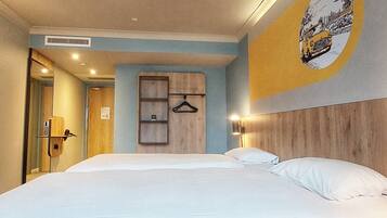 Habitación de hotel con una cama grande, cabecera de madera, perchero en la pared y puerta que da a un baño.