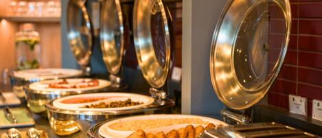 Un buffet composé de plusieurs récipients contenant différents plats et d’ustensiles de service.