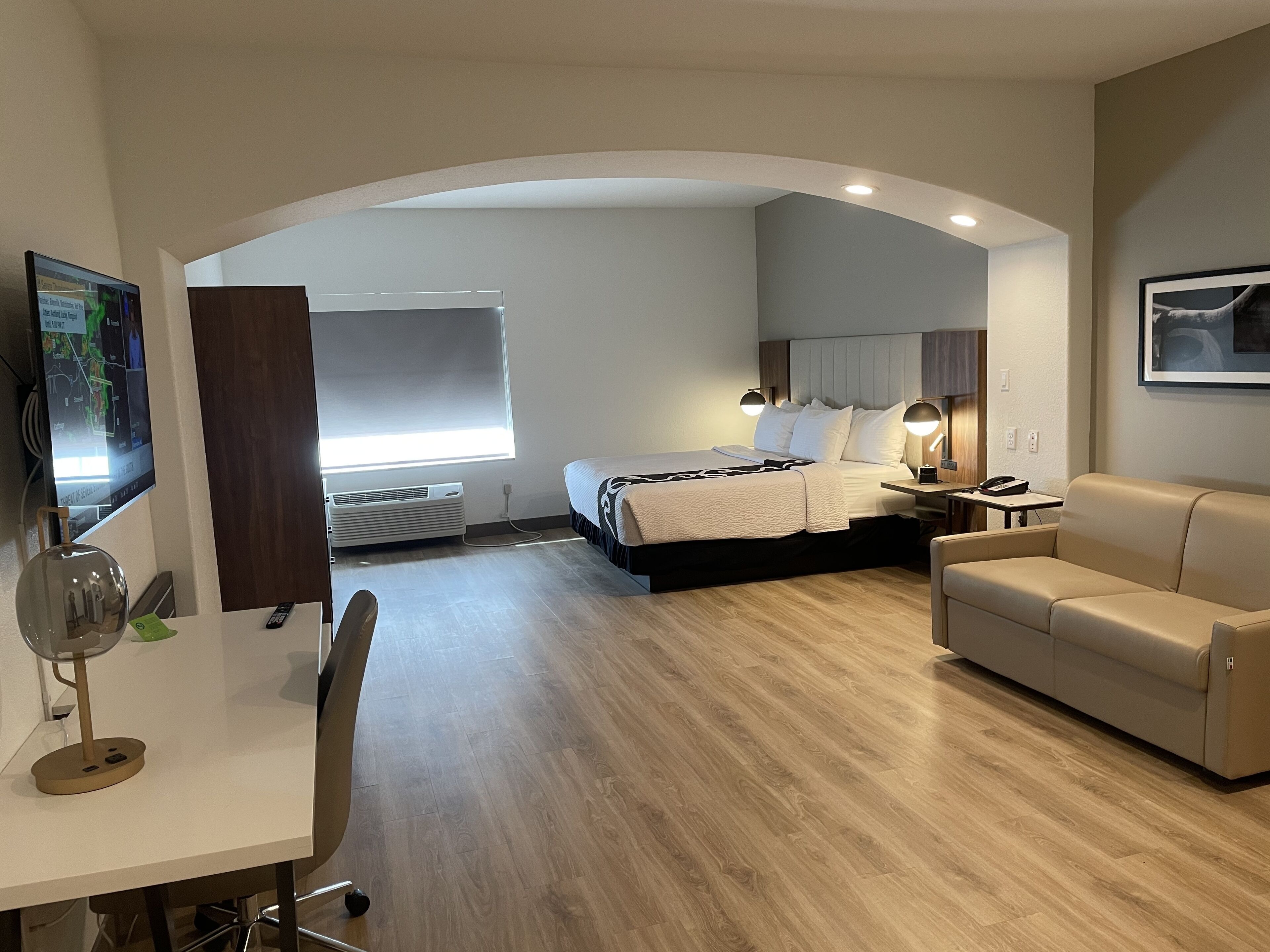 Une chambre d’hôtel équipée d’un lit, d’un bureau, d’une chaise, d’un canapé et d’une télévision.