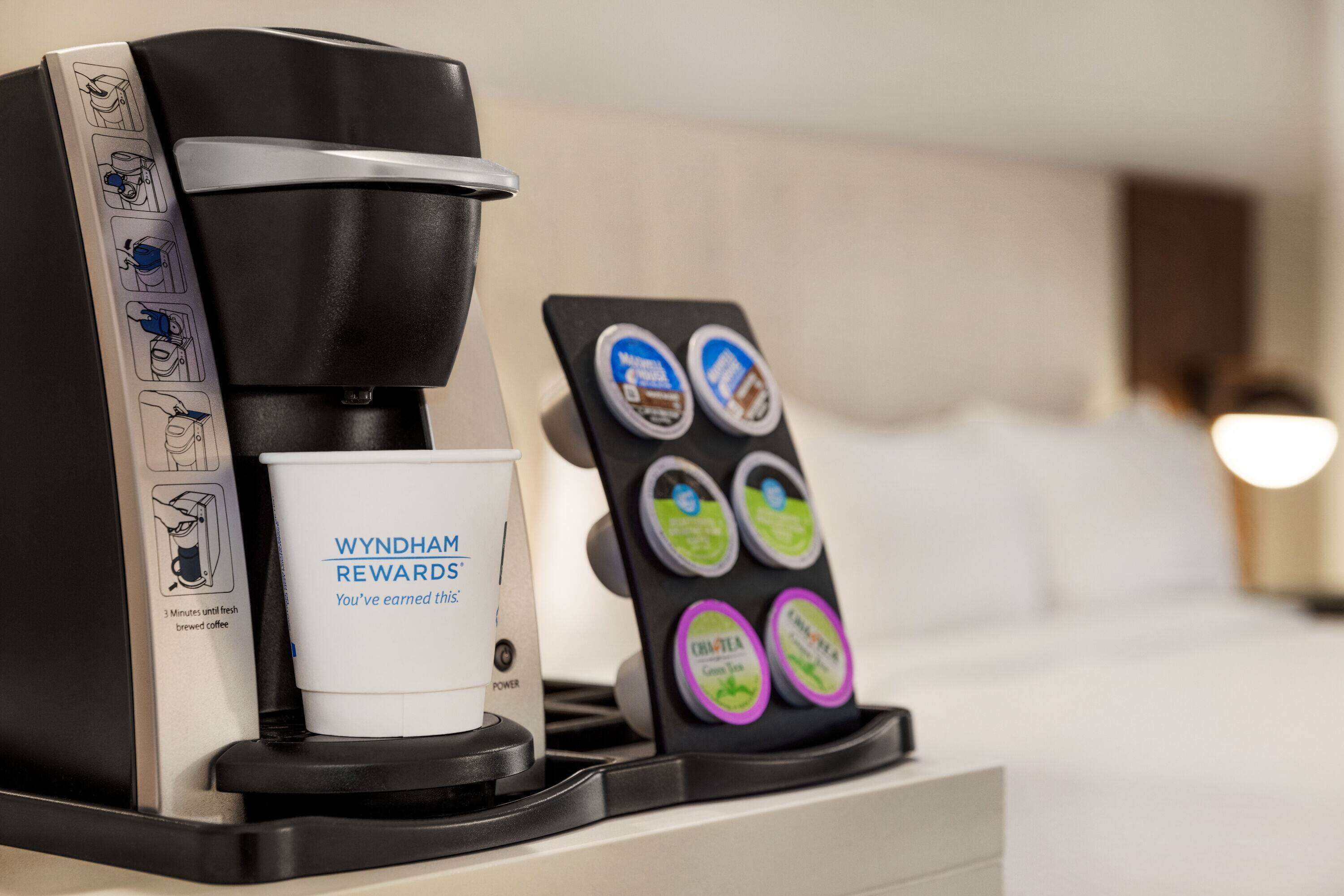 A coffee machine with a cup of coffee and a coffee pod holder with various coffee pod options.