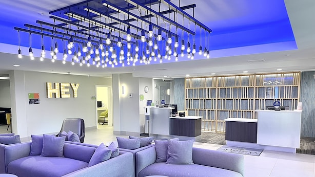 A modern lobby with a reception desk, seating area, and a ceiling with hanging lights. - La Quinta Inn & Suites by Wyndham Port Arthur (Port Arthur)
