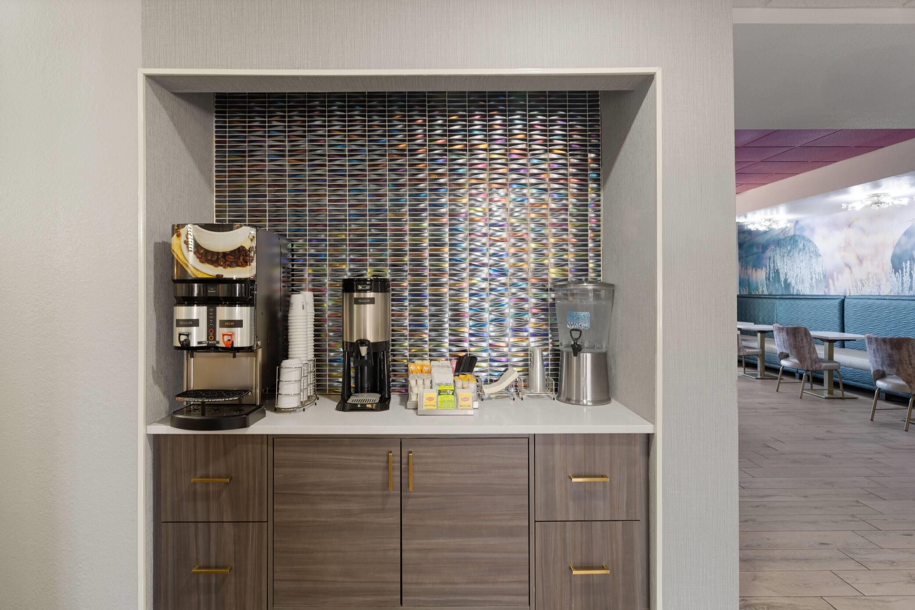 A modern coffee station with a coffee machine, a grinder, and various coffee pods.