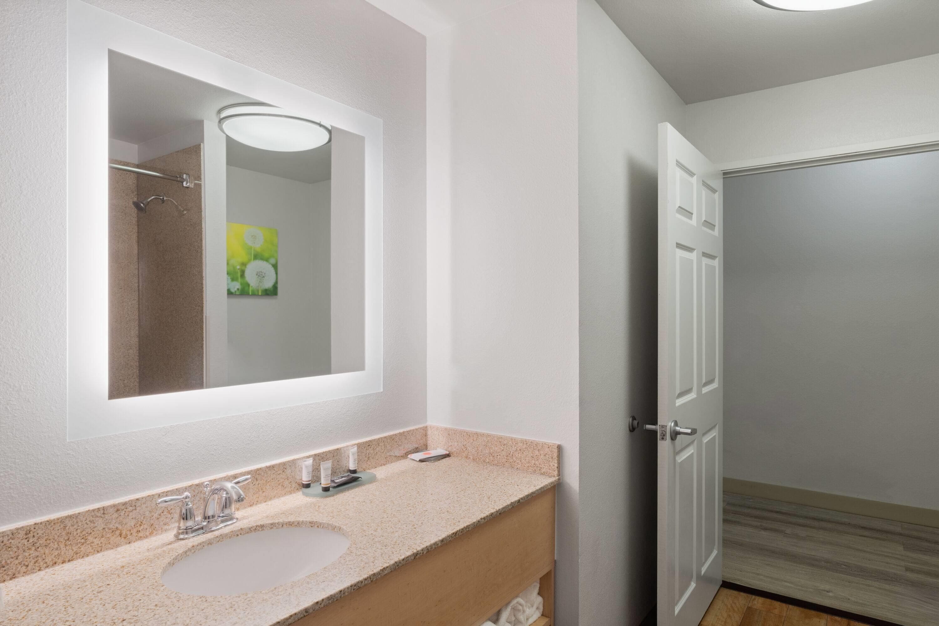 Un baño con un espejo grande, dos lavamanos y una ducha.