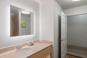 Un baño con un espejo grande, dos lavamanos y una ducha.