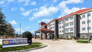A hotel with a red roof and multiple floors, a covered entrance, and a sign reading "La Quinta by Wyndham". - La Quinta Inn & Suites by Wyndham Mt. Pleasant (Mount Pleasant)