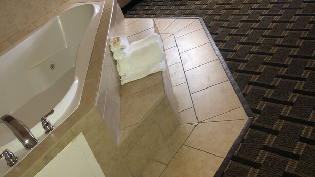 A hotel room with a large bathtub, a neatly made bed, and a mirror above the bed. - La Quinta Inn & Suites by Wyndham Mt. Pleasant (Mount Pleasant)