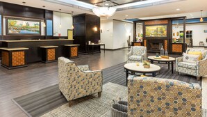 A modern lobby with a fireplace, seating area, and a bar. - La Quinta Inn & Suites by Wyndham Mt. Pleasant (Mount Pleasant)