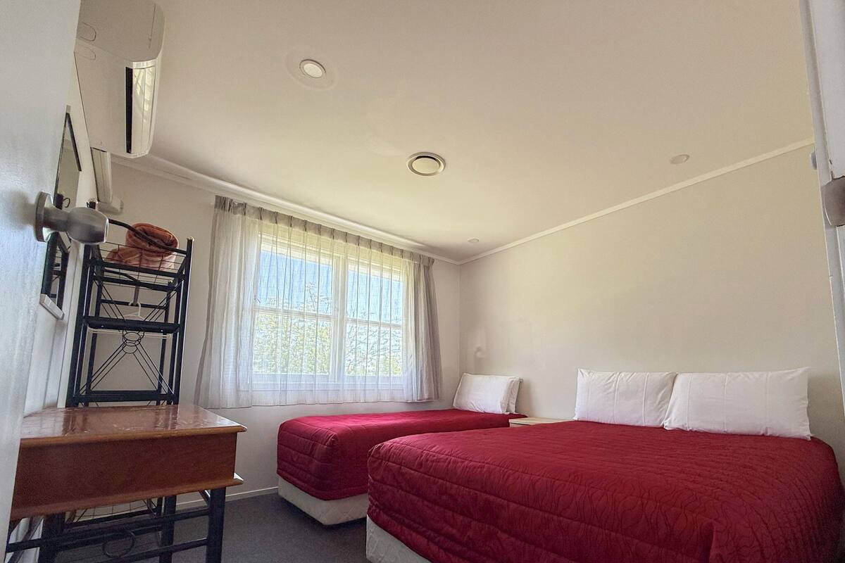 A room with two beds, a desk, and a window with curtains.