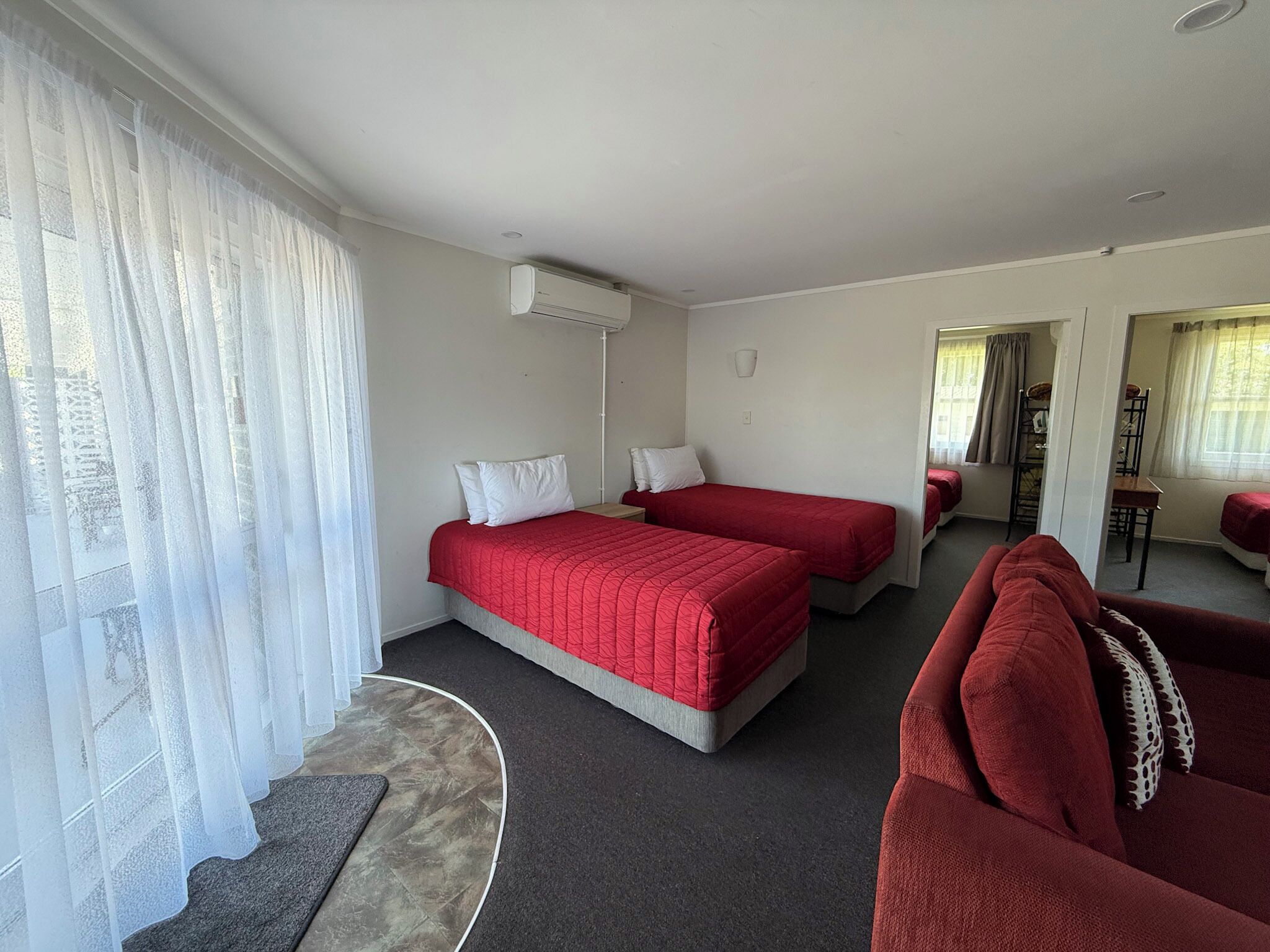 Habitación de hotel con dos camas individuales, un sofá y una zona de comedor.