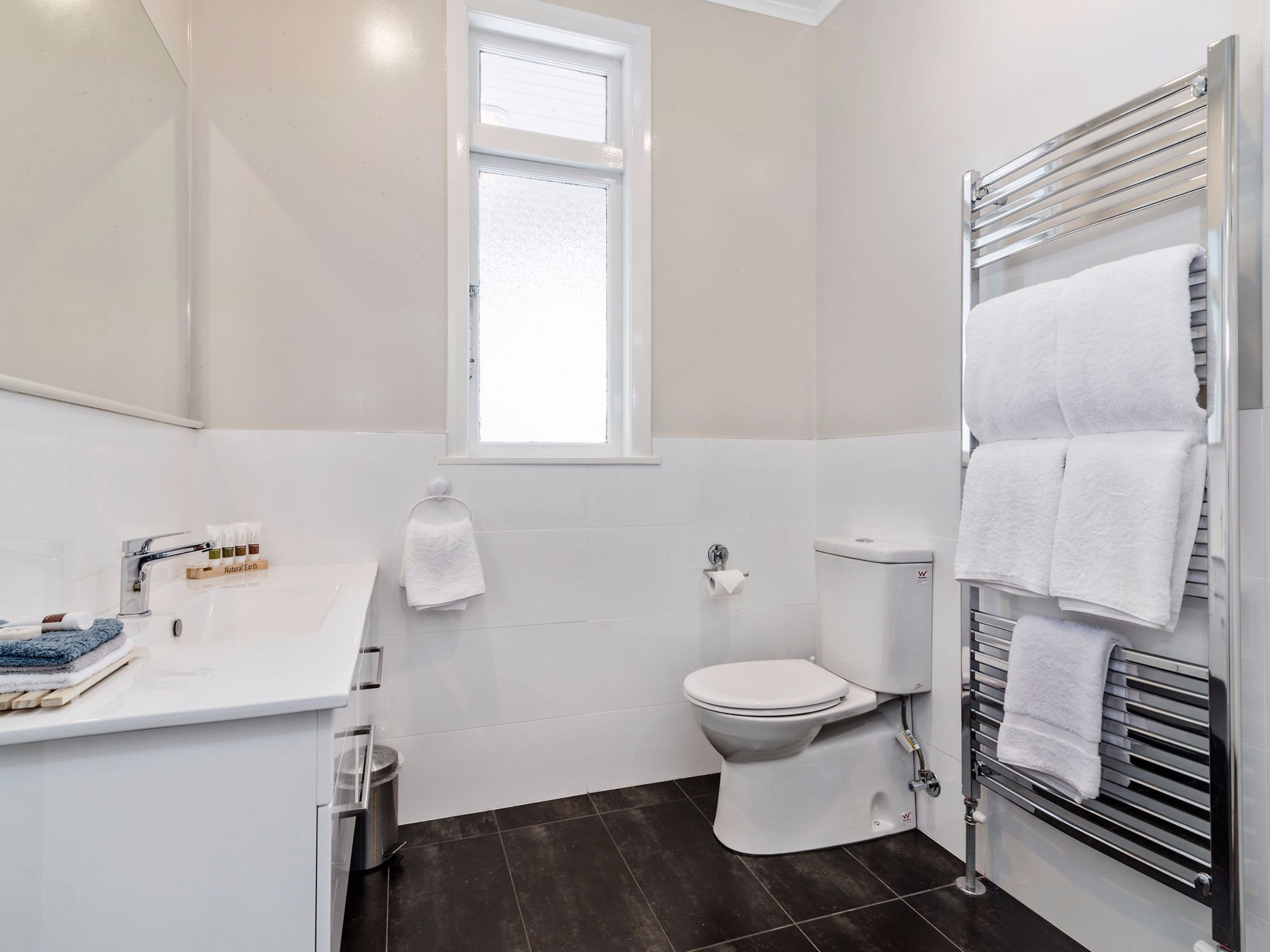A modern bathroom with a toilet, sink, and towel rack.