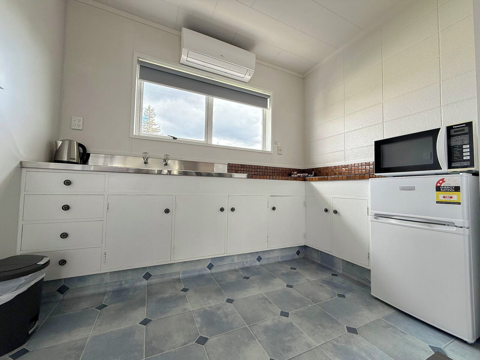 A compact kitchen with white cabinets, a microwave, and a refrigerator.