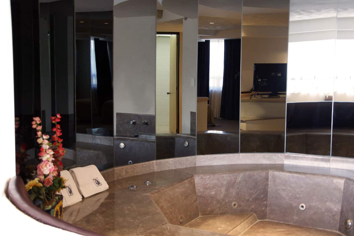 Un baño moderno con una bañera grande, un espejo y un lavabo.