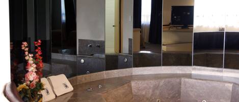 Un bagno moderno con una vasca da bagno ampia, uno specchio e un lavabo.