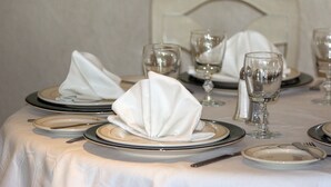 Taula preparada per dinar, amb plats, coberts i vasos de vi.
