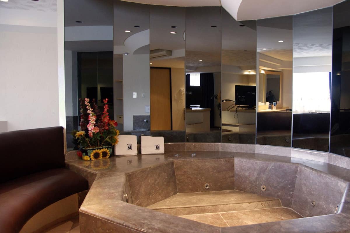 Un vestíbulo moderno con una zona de estar curva, un mostrador de recepción y un espejo grande que refleja el interior.