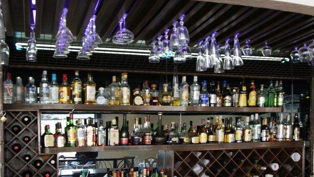 Un bar amb prestatges plens de diferents ampolles de licors i vasos.