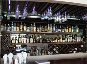 Un bar dont les étagères sont remplies de différentes bouteilles d’alcool et de verres.