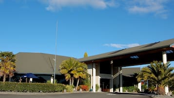 Set amidst lush landscaping, this hotel features a striking reception area under a red-roofed structure.