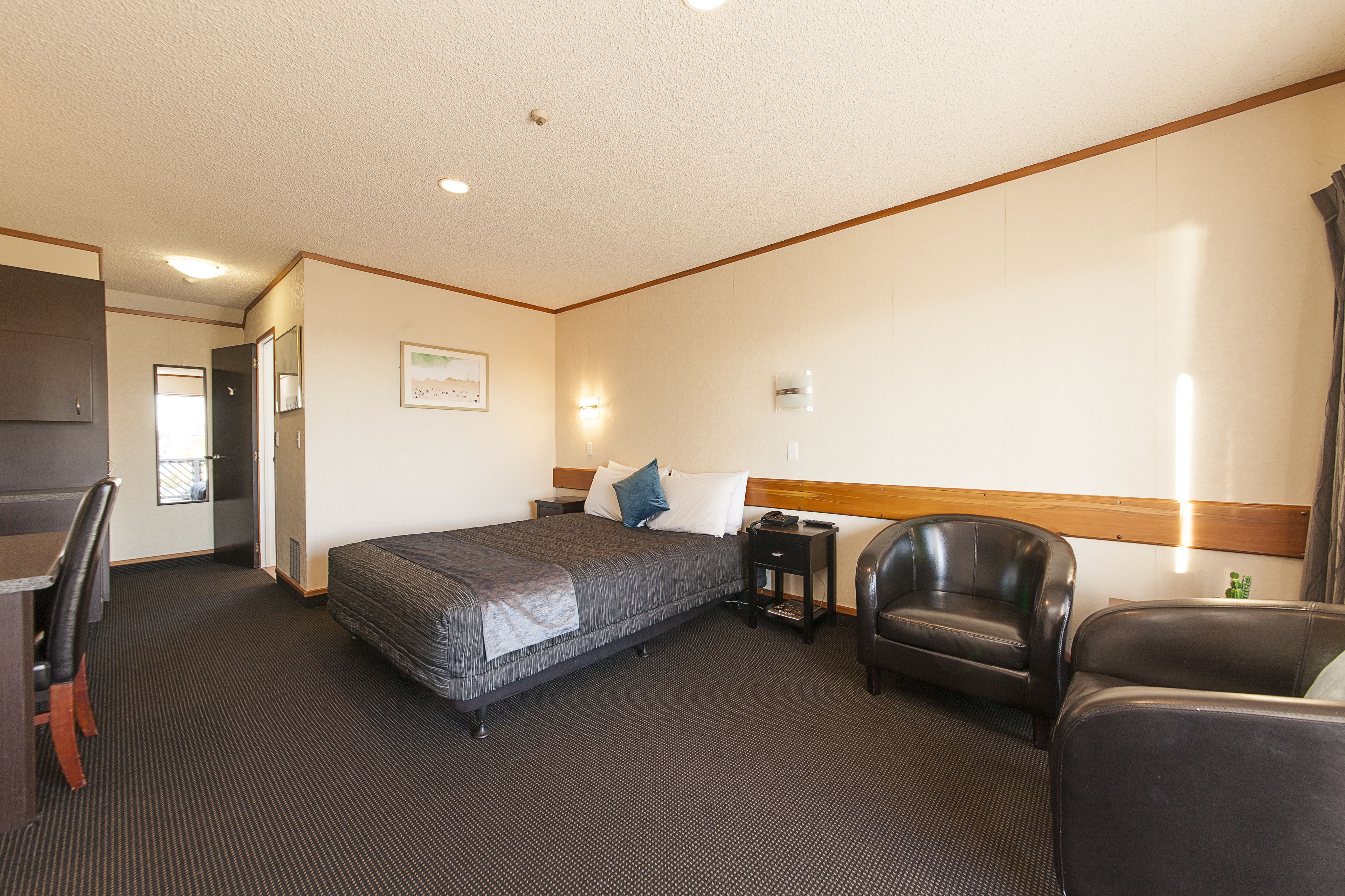 Ein Hotelzimmer mit Bett, Schreibtisch, Stuhl und Nachttisch.