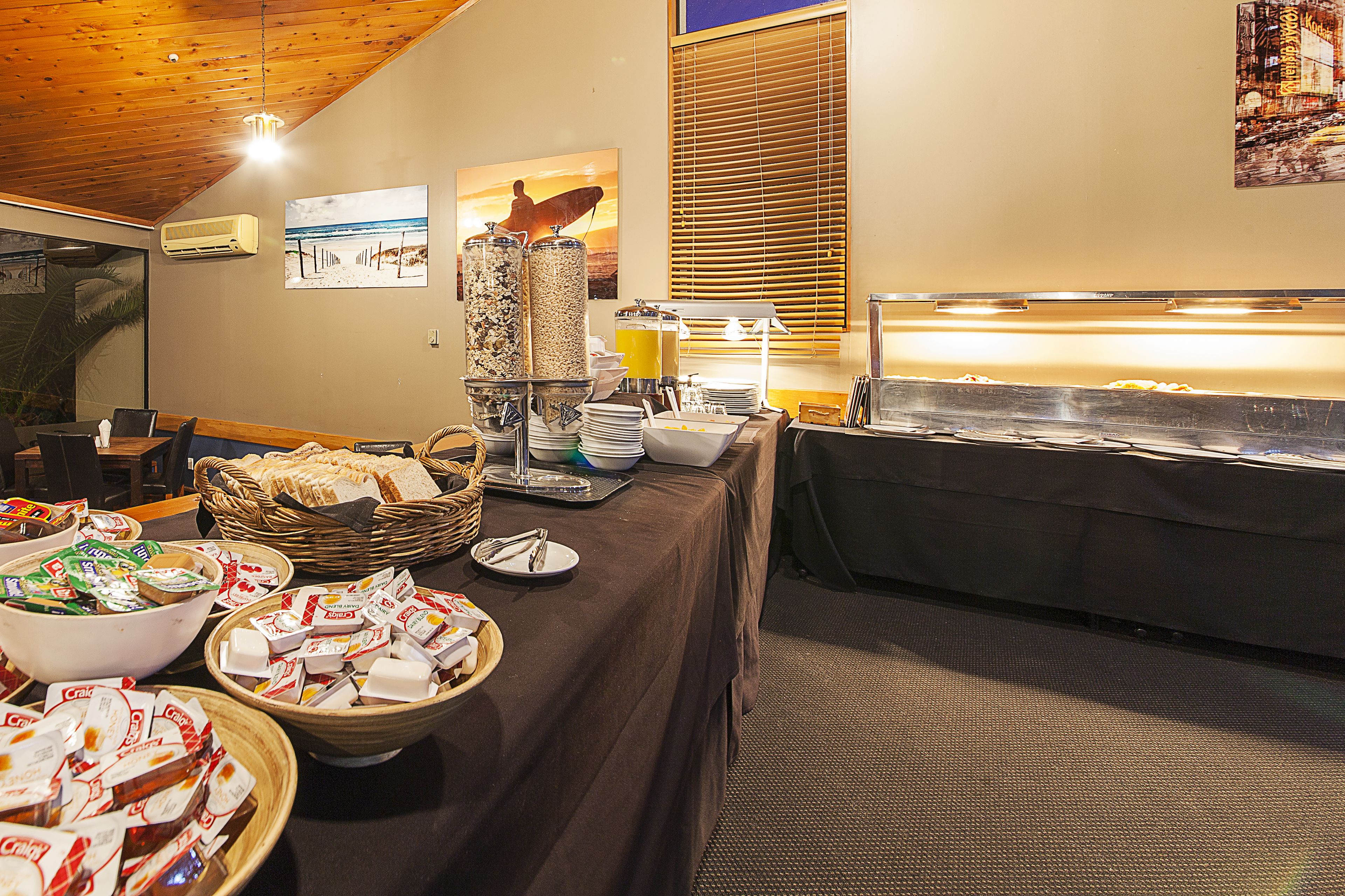 A buffet setup with various food items, a fruit bowl, and a juice dispenser.