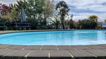 Una piscina al aire libre, sombrillas, sillones reclinables de piscina