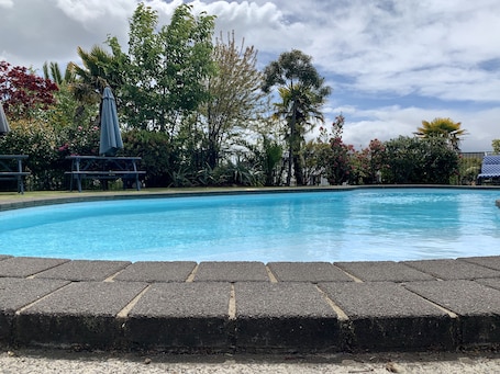 Una piscina al aire libre, sombrillas, sillones reclinables de piscina