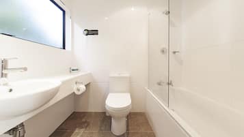 Un baño con lavamanos, inodoro y bañera blancos.
