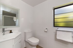 Un baño moderno con lavamanos, inodoro y un espejo grande.