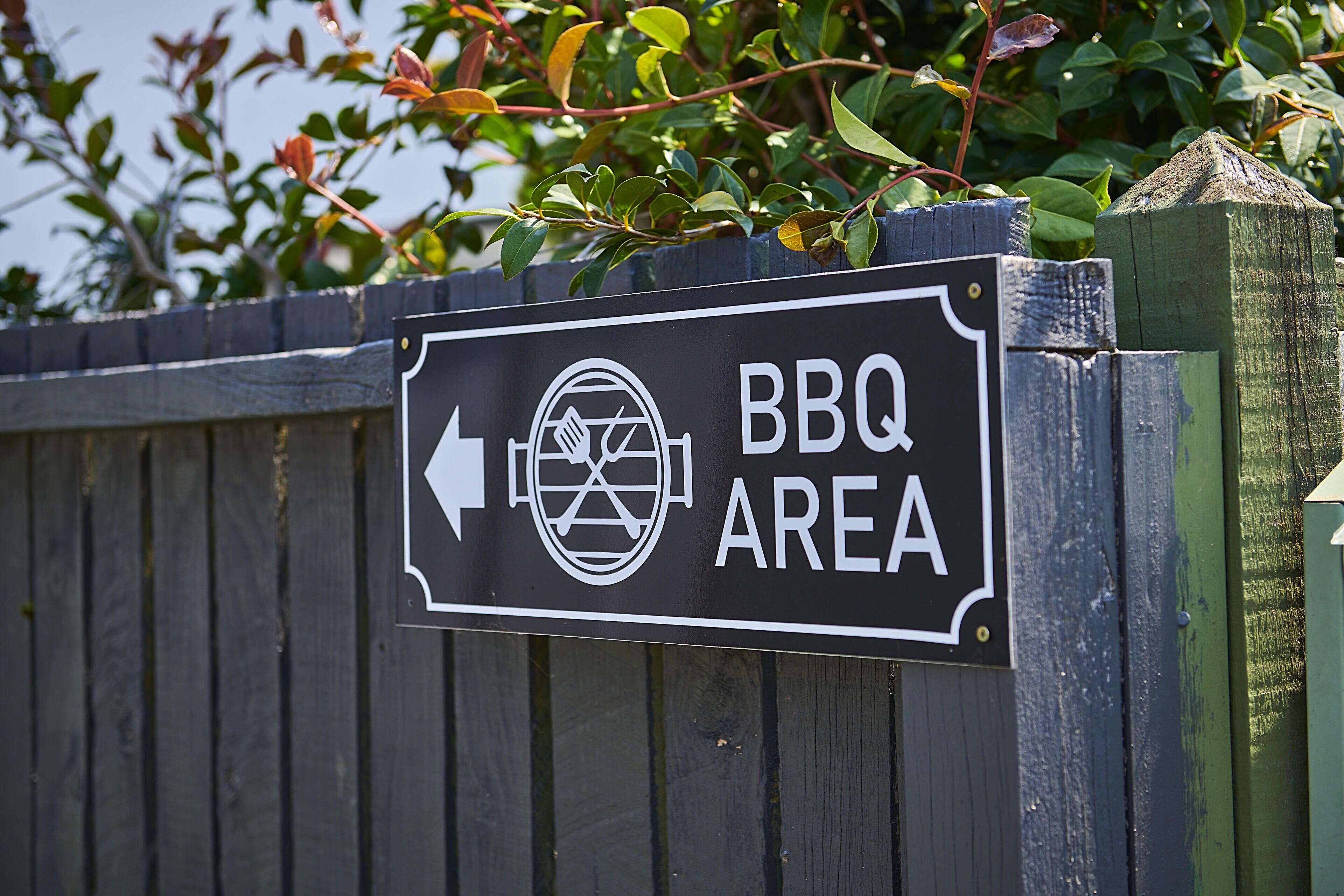Señal que indica un área de barbacoa con una flecha direccional.