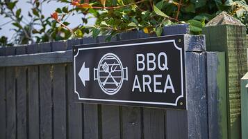 Señal que indica un área de barbacoa con una flecha direccional.