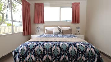 Una camera da letto con un letto, due lampade sui comodini, una finestra con tende e vista sull'esterno.