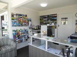 Un comptoir d’accueil avec des brochures de voyage, un calendrier et une horloge au mur.