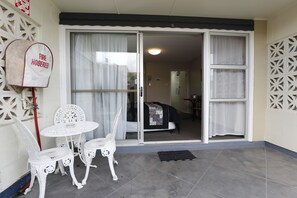 A room with a sliding glass door, a white table with chairs, a fire hose reel, and a patterned wall.